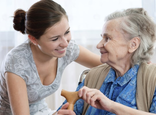 A women smiling at an elderly lady in a wheel chair