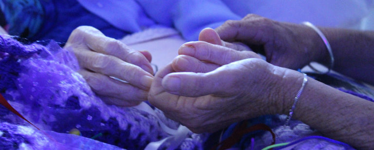 Two hands supporting an elderly person