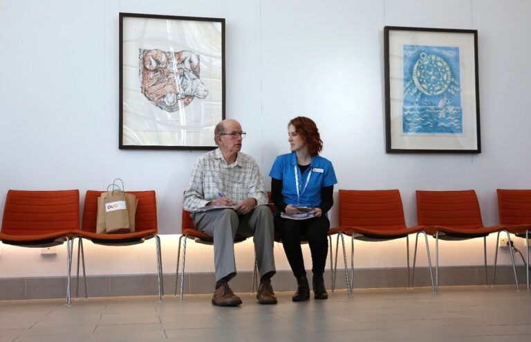 Older man sitting with Expo worker on chairs