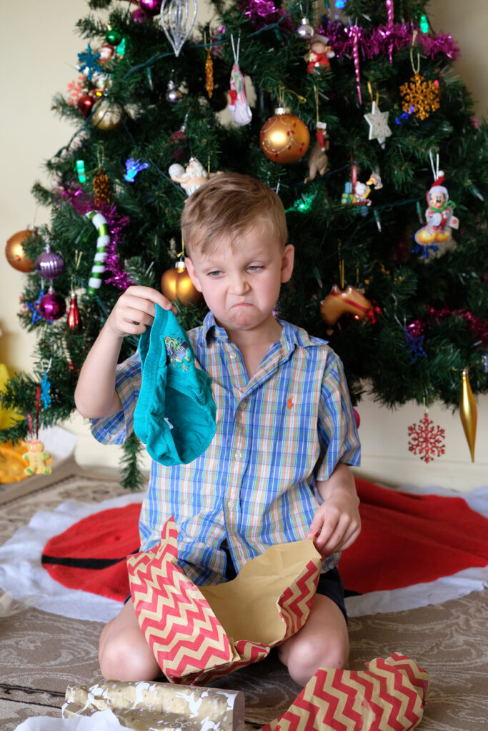 Young boy unwraps unwanted gift